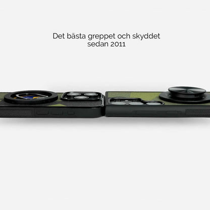 Lähikuva älypuhelimien kameroista, jotka on suojattu M90-maastokuvioisilla suojakuorilla. Kuori sopii iPhone-, Samsung-, OnePlus- ja Google Pixel -puhelimiin. Tekstissä mainitaan "Paras ote ja suojaus vuodesta 2011". Lastu